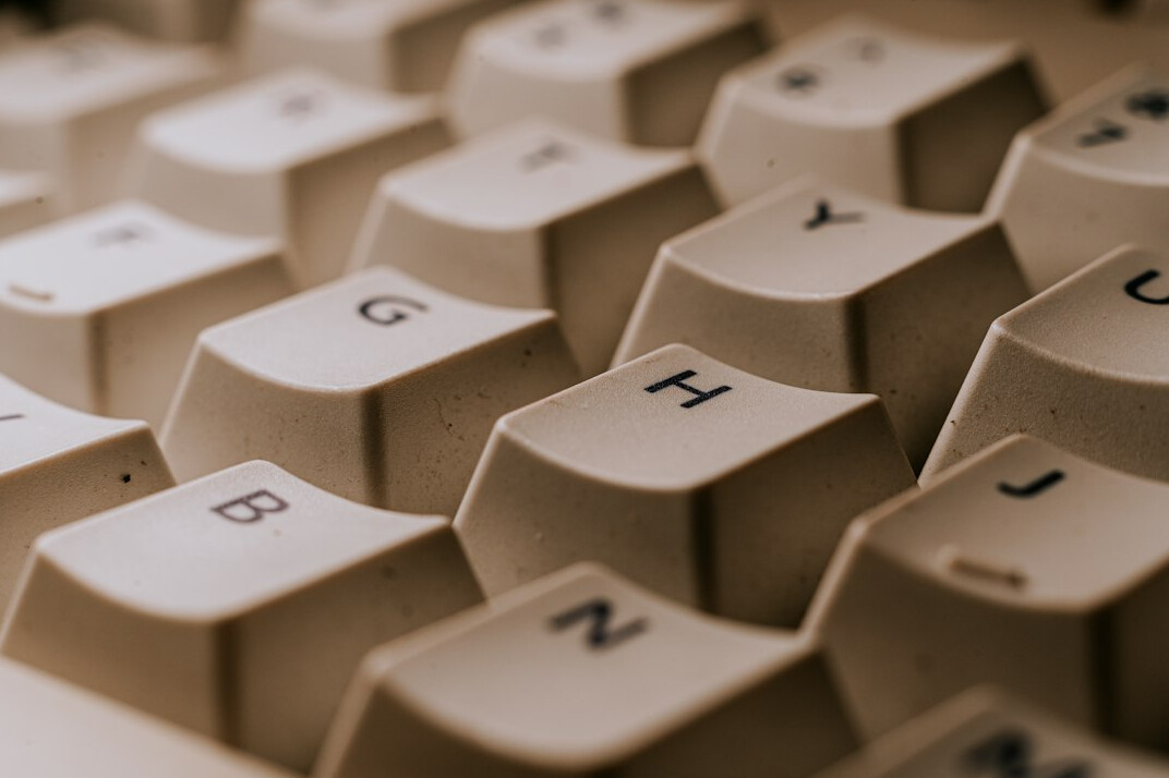 Close-up of hands typing code on a laptop keyboard next to printed documents